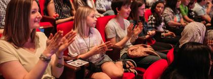 Students clapping in an auditorium 