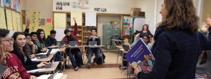 Teacher in classroom with students raising hands