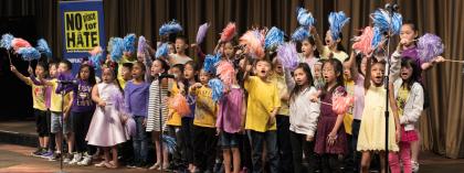 Students performing on stage smiling