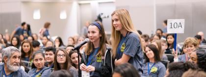 Two students standing in audience