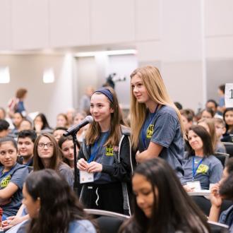 Two students standing in audience