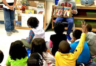 Student reading books to other students