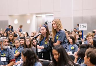 Two students standing in audience